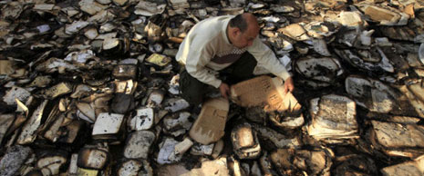 Доброволец събира обгорели книги от хранилището на Египетсткия институт в Кайро, декември 2011г.