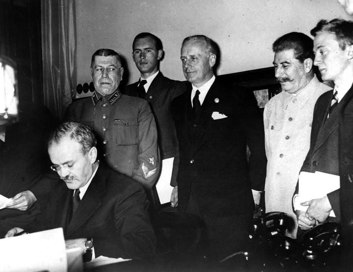Съветският външен министър Вячеслав Молотов подписва пакта за ненападение между Германия и СССР. На заден план са Йоахим фон Рибентроп и Йосиф Сталин (23 август 1939 г.).